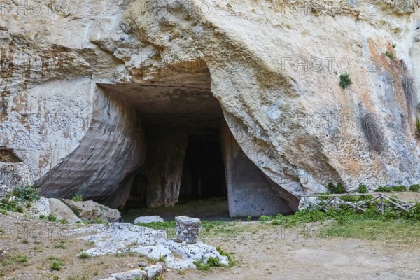 Rope grotto, Large opening to a cave in a rocky landscape surrounded by grass, Neapolis Archaeological Park, Syracuse, Sicily, Italy, Europe