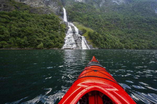 Kayak trip on the Geirangerfjord at the Freier waterfall, tip of a red kayak in the fjord, atmospheric fjord landscape, first person view, near Geiranger, Møre og Romsdal, Norway, Europe
