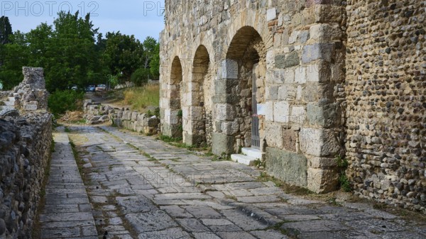 Historic stone street next to an ancient wall with arches, Basilica, Street, Archaeological site, Western excavation, Kos town, Kos, Dodecanese, Greek Islands, Greece, Europe