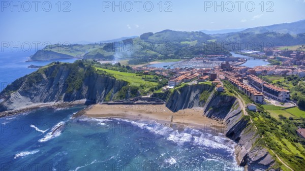 Breathtaking aerial perspective of zumaia's dramatic cliffs, golden beaches, and charming town nestled along the vibrant bay of biscay coastline in the basque country, Spain.
