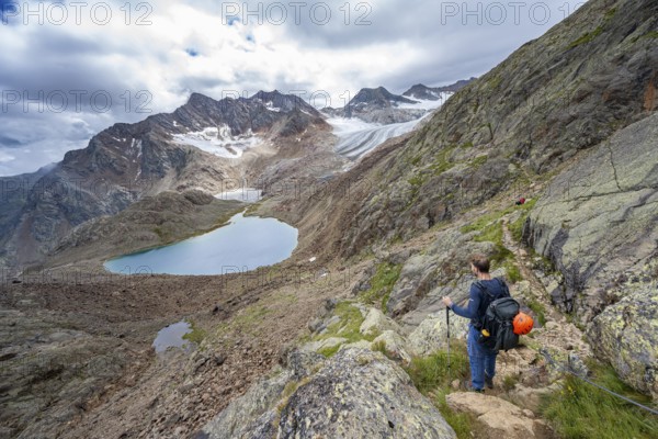 Mountaineer in rocky high mountain landscape, view of mountains with mountain lake Vogelhüttensee and glacier Übeltalferner, Stubai Alps, South Tyrol, Italy, Europe