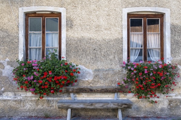 Two windows with flower boxes and wooden bench on a charming stone wall, Umrathshausen, Bavaria, Germany, Europe