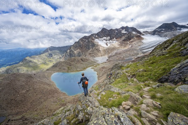 Mountaineer in front of dramatic high mountain landscape, view of mountain lake Vogelhüttensee and glacier Übeltalferner, Stubai Alps, South Tyrol, Italy, Europe