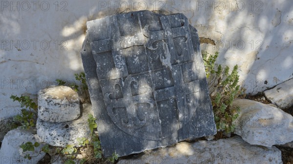 Ancient tombstone with inscriptions, surrounded by vegetation and shade, Church of Agia Paraskevi, Antimacheia, Medieval Fortress, St John's Fortress, Antimachia, Kos, Dodecanese, Greek Islands, Greece, Europe