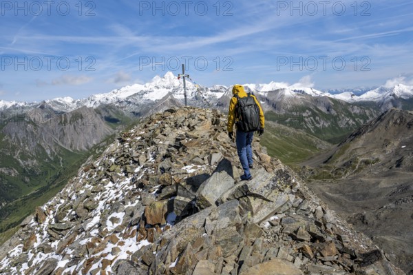 Mountaineers at the summit of Böses Weibl with summit cross and colourful prayer flags, view of picturesque mountain landscape with snow-covered summit of the Großglockner, Wiener Höhenweg, Schober group, Hohe Tauern National Park, Carinthia, Austria, Europe