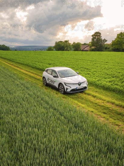 A car drives next to vast fields along a rural road under a cloudy sky, Deer E- CarSharing, Renault Megane electric car, Calw, Black Forest, Germany, Europe