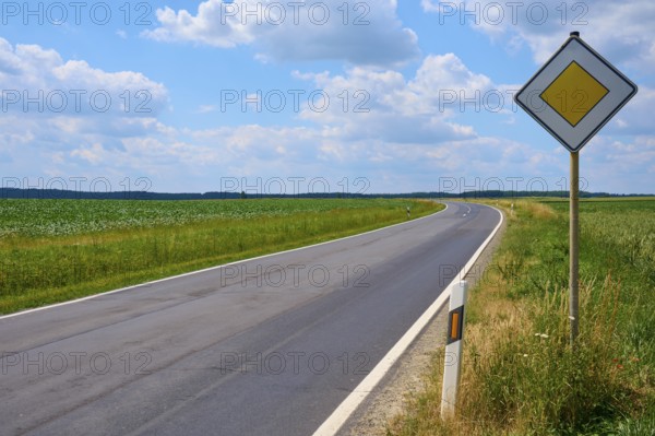 Empty, winding road with traffic sign and wide sky with clouds, Hausen, Würzburg district, Mainfranken, Bavaria, Germany, Europe