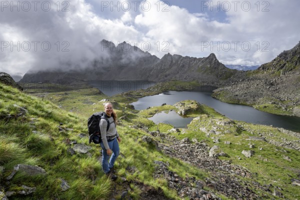 Mountaineer on hiking trail, view of mountain landscape with mountain lakes Wangenitzsee and Kreuzsee, cloudy mountain peaks in the morning light, Schober Group, Hohe Tauern National Park, Carinthia, Austria, Europe