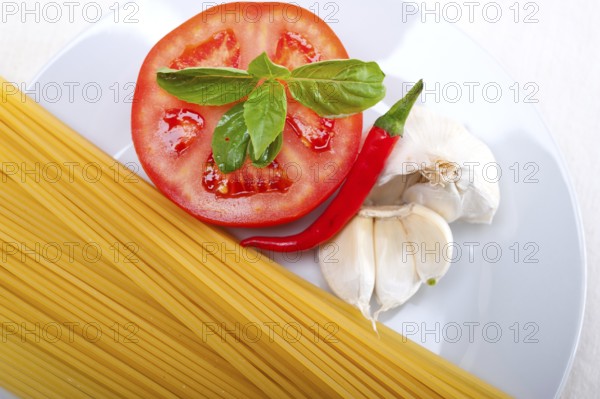 Italian spaghetti pasta tomato raw ingredients basil garlic and red chili pepper