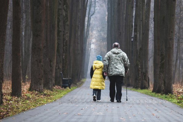 Grandfather and granddaughter walking together in the park