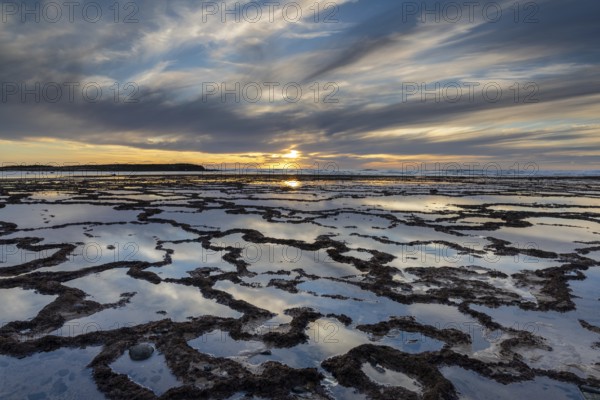 A beautiful sunset over the ocean with rocky beach and tidal pools in the foreground