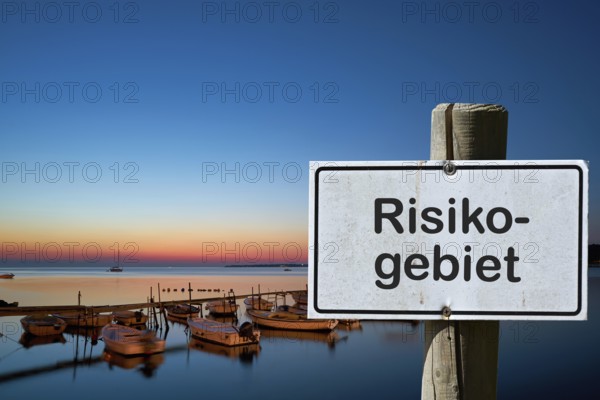Sign with the inscription risk area. Due to many new corona infections, areas are designated as risk areas
