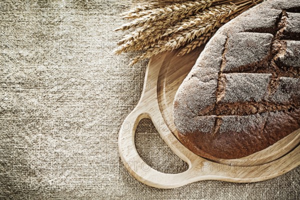 Carving board bread rye ears on burlap background