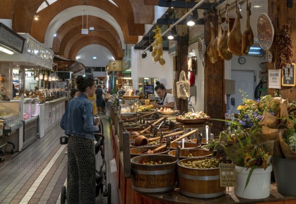 Cork, Ireland, 16 August, 2022: customers buying food at a market stall with Spanish delicacies and Iberico Hams, Europe