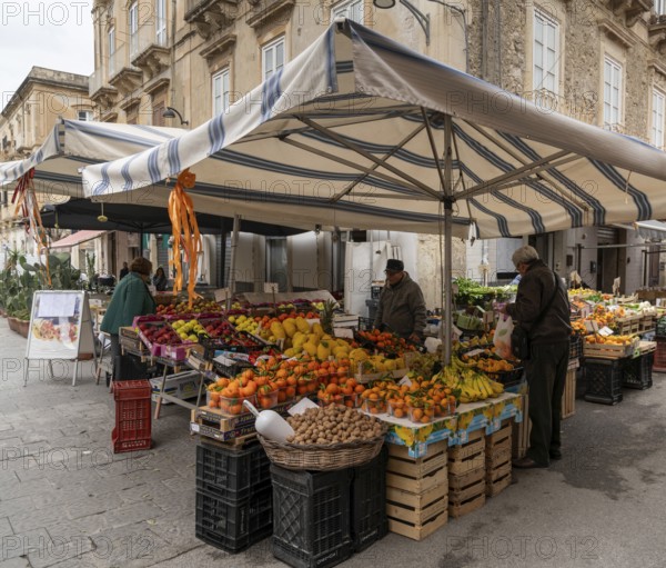 Syracuse, Italy, 28 December, 2023: greengrocer selling fruit and vegetables to customers in the Syracuse market, Europe