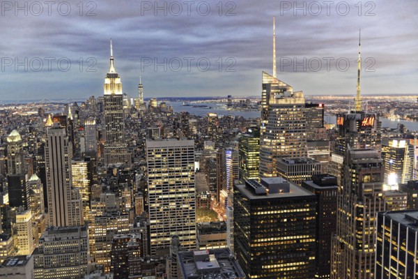 Rockefeller Center observation deck, panoramic view of the dense New York City skyline, skyscrapers are illuminated in the evening skyline under a cloudy sky, Manhattan, New York City, New York, USA, North America