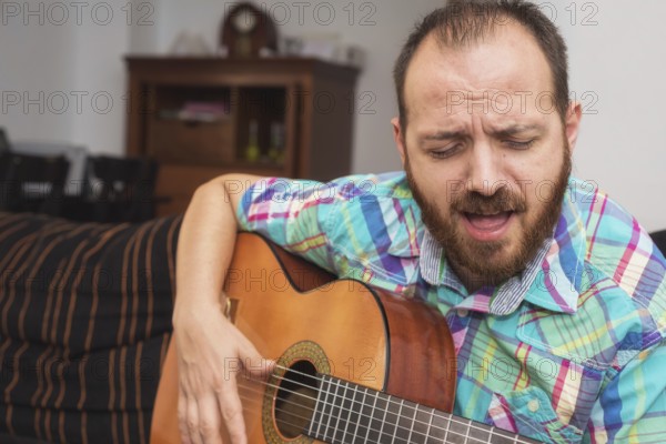 Young man musician playing acoustic guitar
