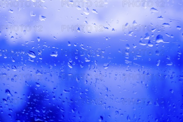 Raindrops on a window, illustrating gray and rainy weather during the day. Black and white grayscale