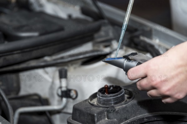 Automotive technology - Mechanic checks coolant in a car workshop during a car service, close-up