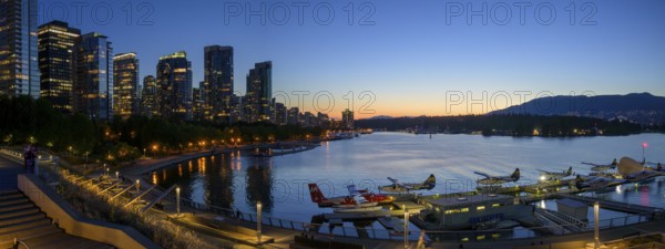 Harbour view at sunset with seaplanes and illuminated skyline in the background, Vancouver, British Columbia, Canada, North America