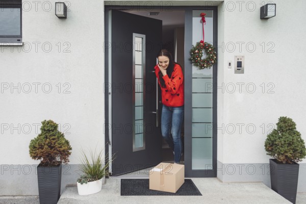 Cheerful young woman excited over a package she just received. Woman getting her christmas gift in the mail. Opening the Christmas present at home