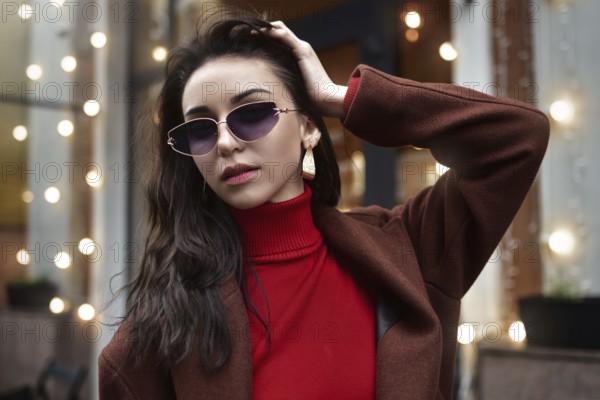 Portrait of a Woman in sunglasses fixing her hair on the street