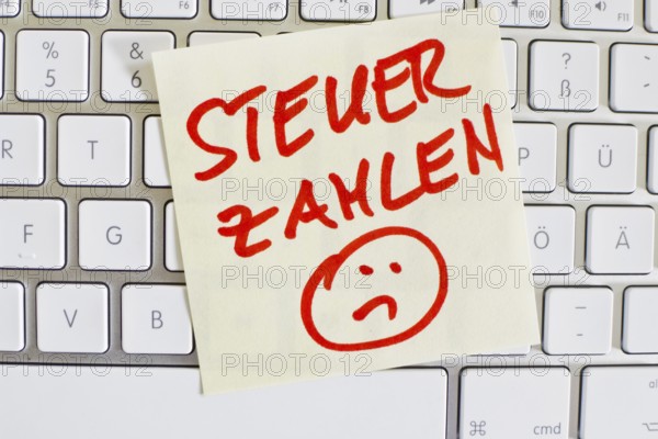 A note on the keyboard of a computer as a reminder: Pay tax Austria