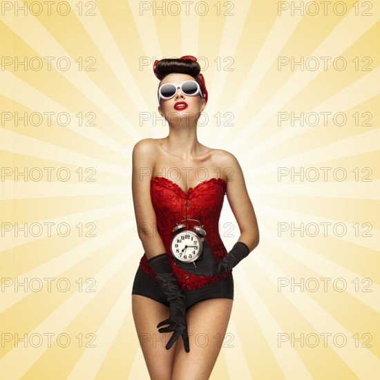Sexy pinup girl in a red vintage corset holding a retro alarm clock and posing on colourful abstract cartoon style background