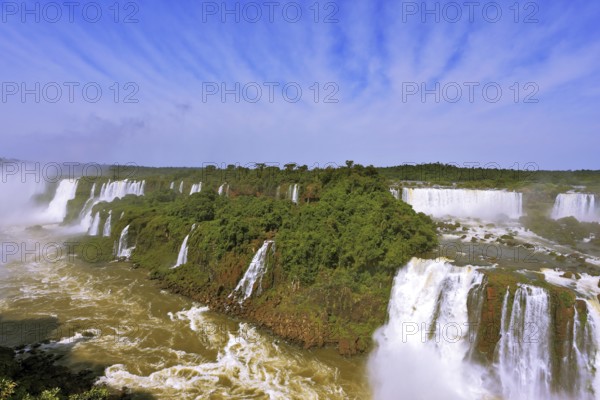 Roaring falls in South America - Iguazu. Foamy streams fall between the green jungle. The magnificent rainbow is shone in a water dust