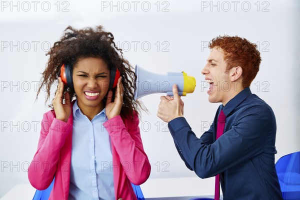 Businessman shouting in megaphone to african executive with scared expression