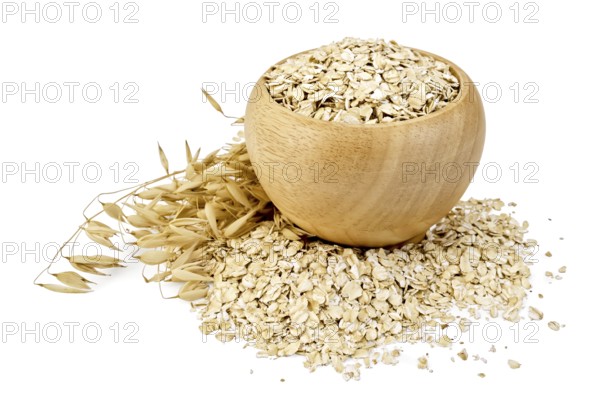 Oat flakes in a wooden bowl, oat stalks, oat flakes scattered on the table, against a white background