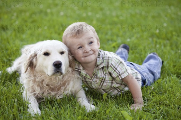 Cute toddler blonde boy with golden retriever hugging close up