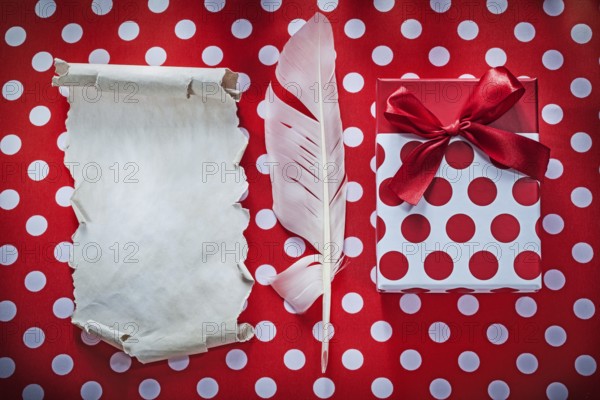Present box vintage sheet of paper plume on polka-dot red table cloth celebrations concept