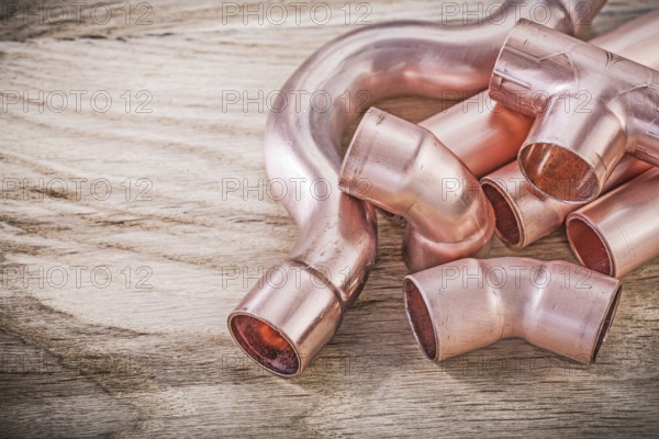 Copper water pipe connectors on wooden board plumbing brassware concept