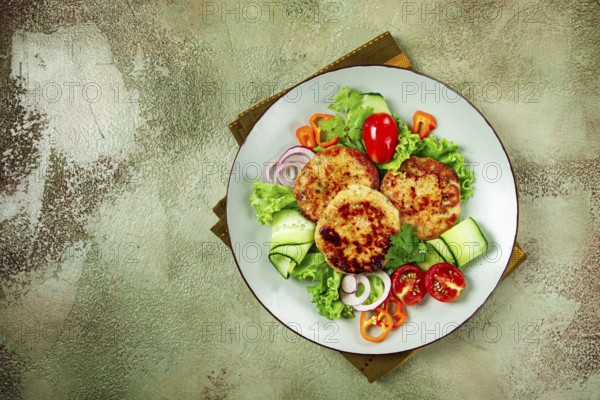Fried chicken cutlets, minced chicken, with vegetables, on a green background, with vegetable salad, top view, homemade, no people