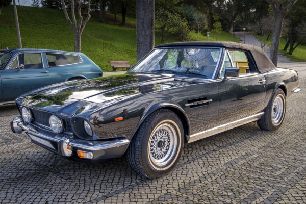 Lisbon, Portugal, Jan 20, 2024: Classic brown Aston Martin V8 Volante grand tourer parked on a cobblestone road, know as Britain first supercar, 2-door coupe convertible, Europe