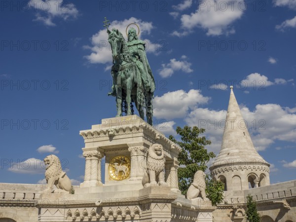 Equestrian statue with lions and a surrounding tower in front of a blue sky, budapest, danube, hungary