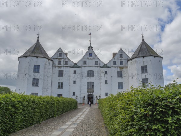 An impressive white castle with several turrets under a cloudy sky, glücksburg, schleswig-holstein, germany