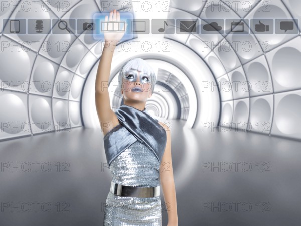 Futuristic kid girl in silver touching finger icons on glass transparent holographic screen