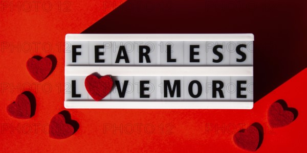 Lightbox with text FEAR LESS LOVE MORE. Motivational Words Quotes Concept with red hearts. Colorful red background. Minimalistic creative concept. Inspirational phrase