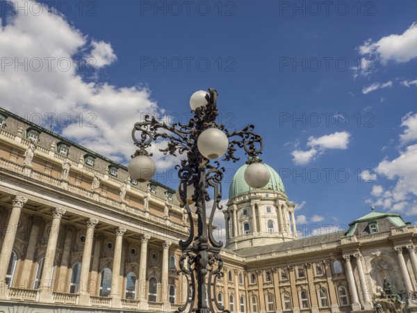 Historic castle with impressive dome and ornately forged lantern under a blue sky with white clouds, budapest, danube, hungary