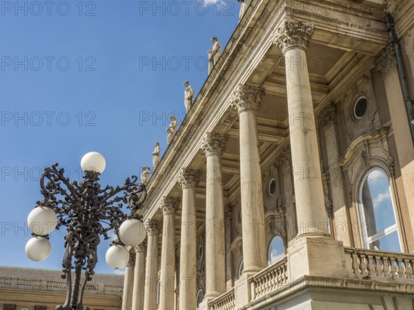 A building with classical columns, decorated with an ornate street lamp and blue sky in the background, budapest, danube, hungary