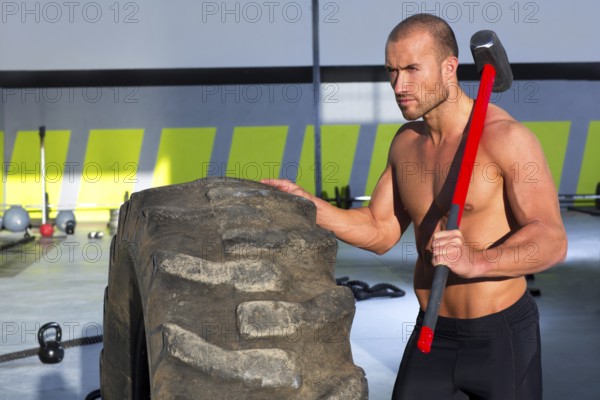 Crossfit sledge hammer man workout at gym relaxed after exercise