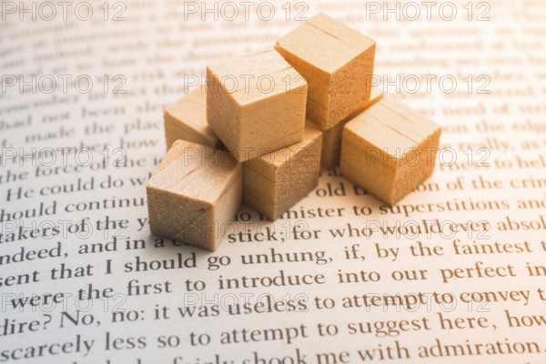 Wooden toy cubes placed on a book page in English