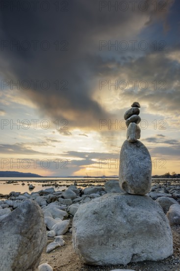 Stone sculpture on the shore of a lake at sunset with dramatic sky, Seegarten, Allensbach, Lake Constance, Baden-Württemberg, Germany, Europe