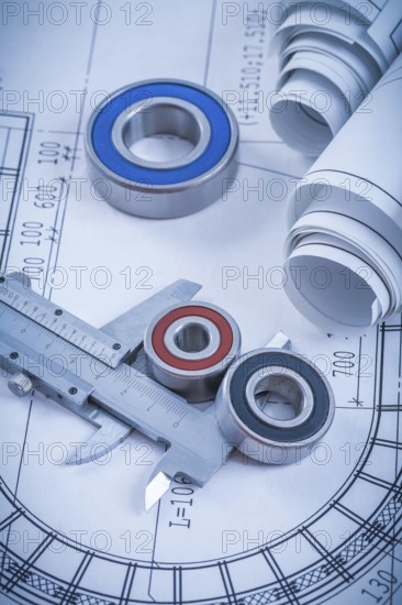 Rolls of construction drawings round rolling bearings and trammel caliper on blueprint industrial concept