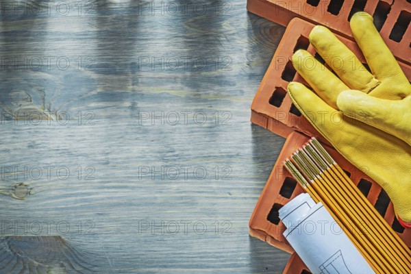 Construction plans protective gloves red bricks wooden meter on wood board bricklaying concept