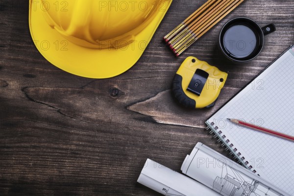 Notepad pencil blueprints instruments of measurement building helmet and coffee on wooden board