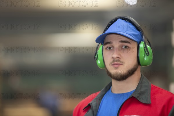 Belarus, Gomil. Wood processing plant. April 25, 2022.Close-up of a male worker wearing soundproof industrial headphones. Portrait of a worker standing in a factory in a workshop, Europe