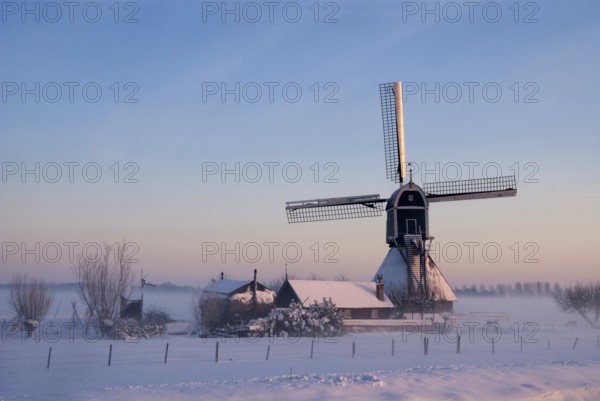 Wingerdse mill near Oud-Alblas in the Dutch region Alblasserwaard in a misty and wintry landscape